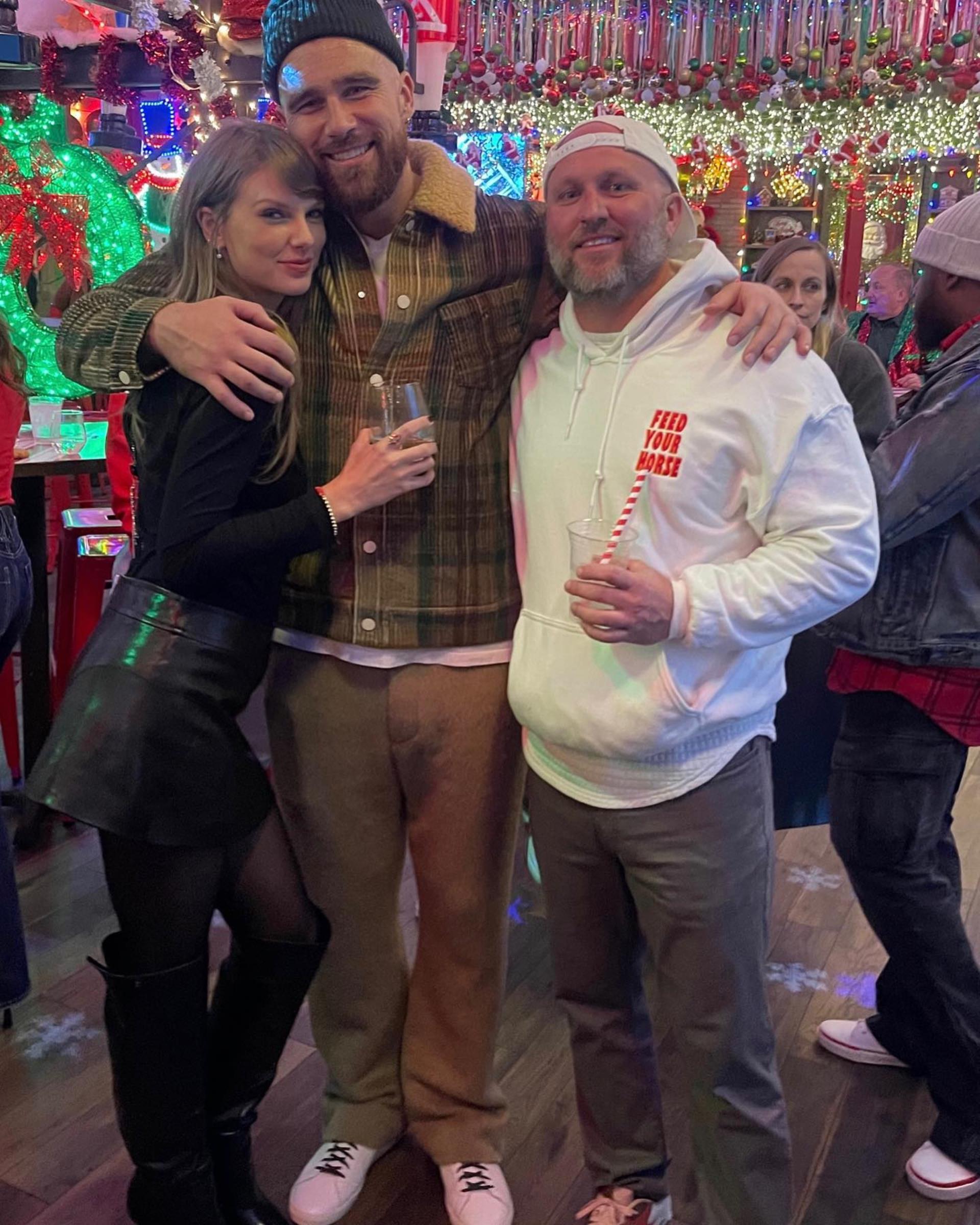 Taylor Swift posing with Travis Kelce and Andrew Spruill.