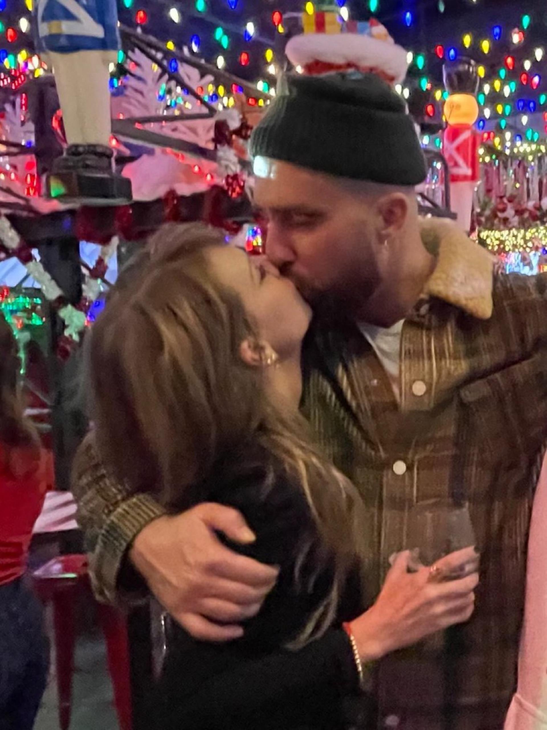 Taylor Swift and Travis Kelce kissing at a holiday party.